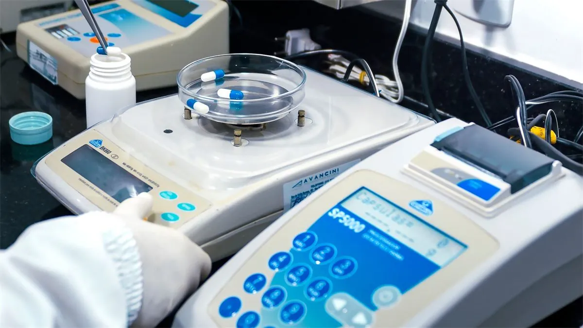 Cápsulas sendo pesadas em balança de precisão dentro de laboratório de controle de qualidade